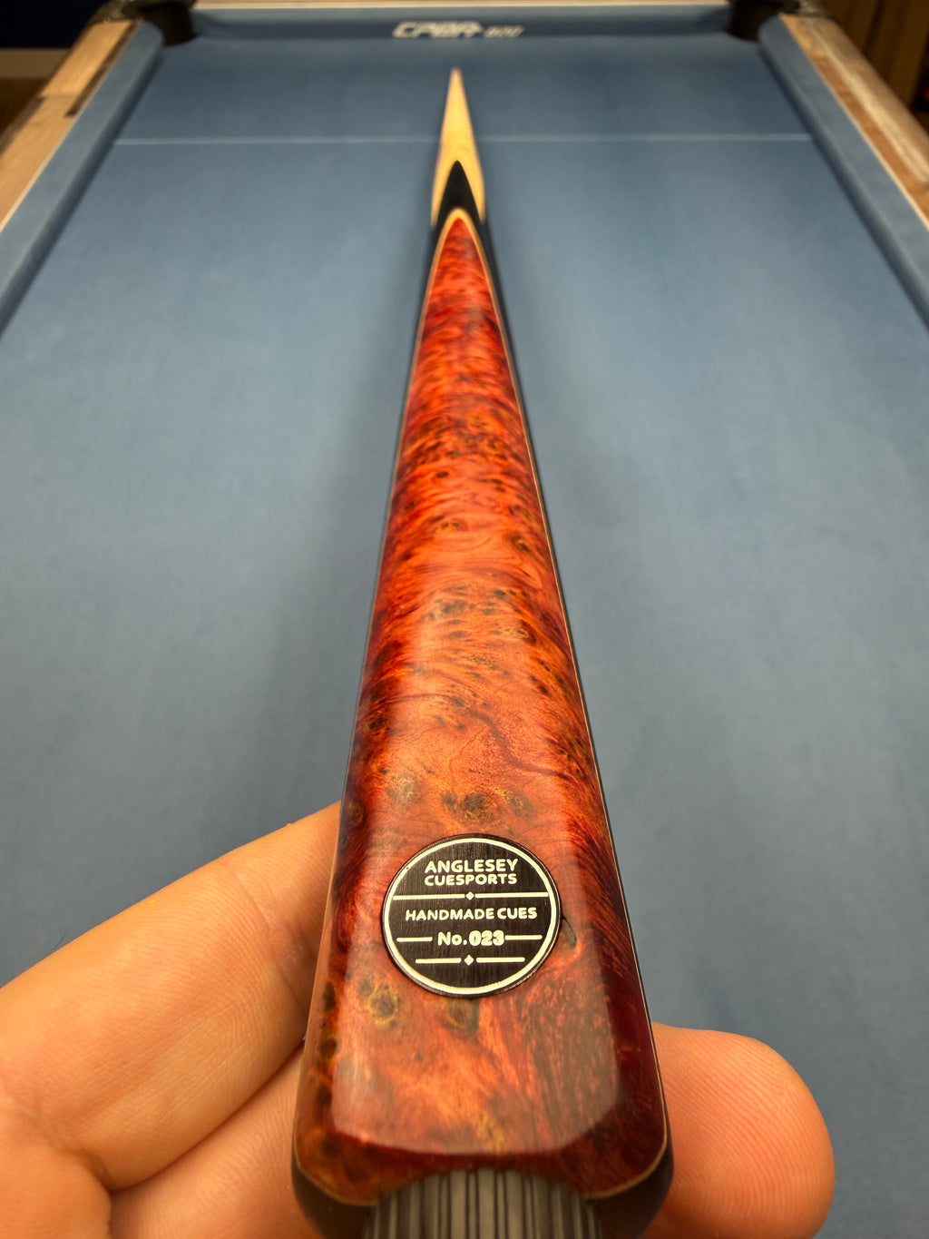 Anglesey Cuesports Red Peacock Cue No.023 - butt close-up showing No.023 badge and auburn burr wood
