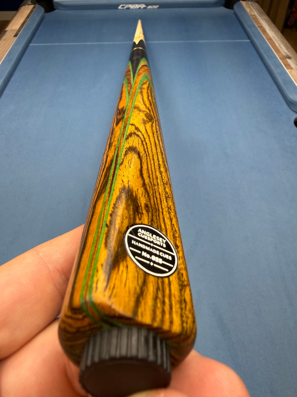 Anglesey Cuesports Zebrawood Cue No.025 - hand-held butt view showing No.025 badge and zebrawood grain